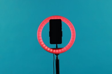 Photo of Ring lamp with smartphone on light blue background