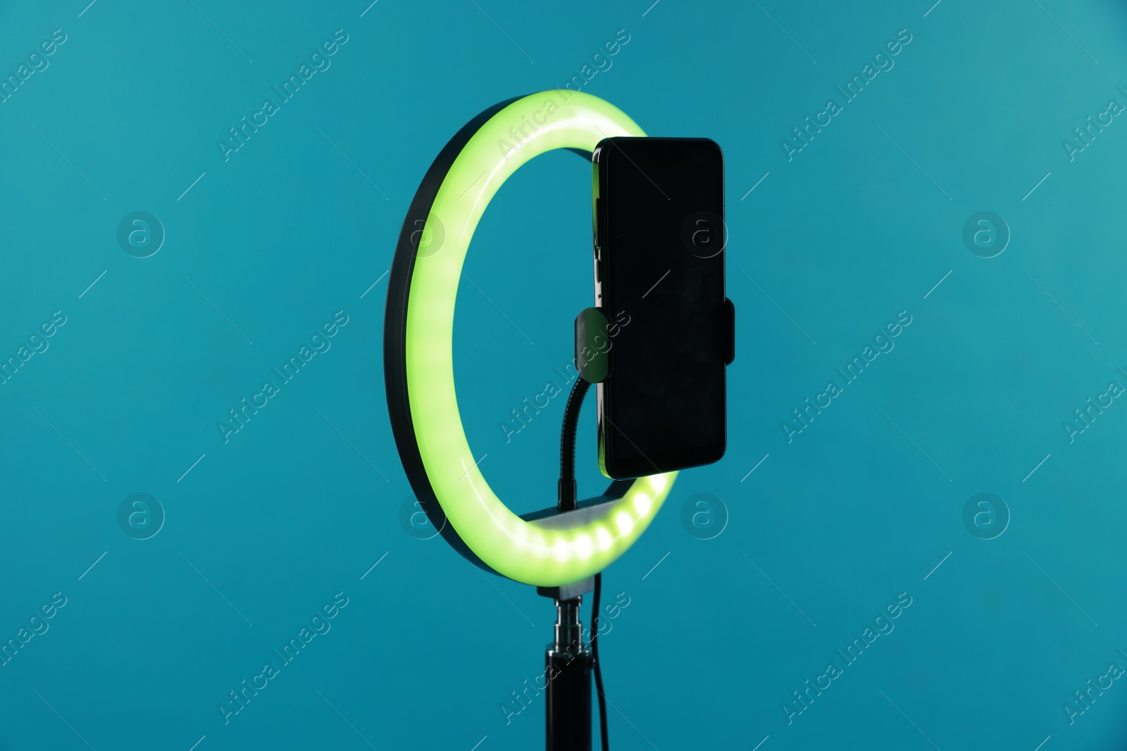 Photo of Ring lamp with smartphone on light blue background