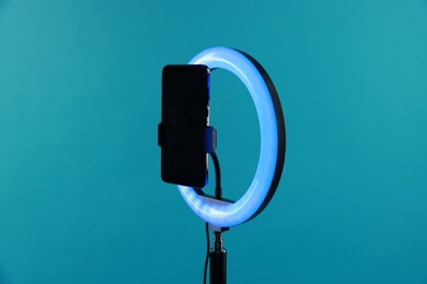 Photo of Ring lamp with smartphone on light blue background