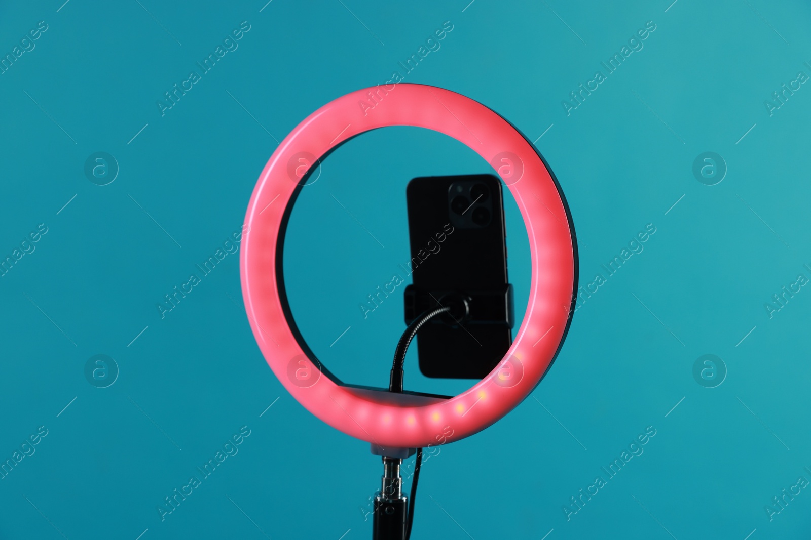 Photo of Ring lamp with smartphone on light blue background