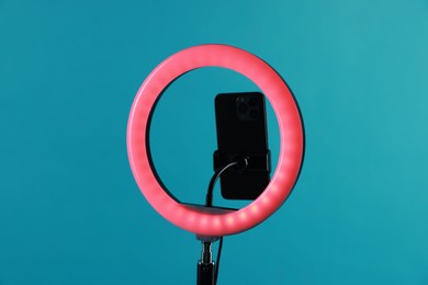 Photo of Ring lamp with smartphone on light blue background