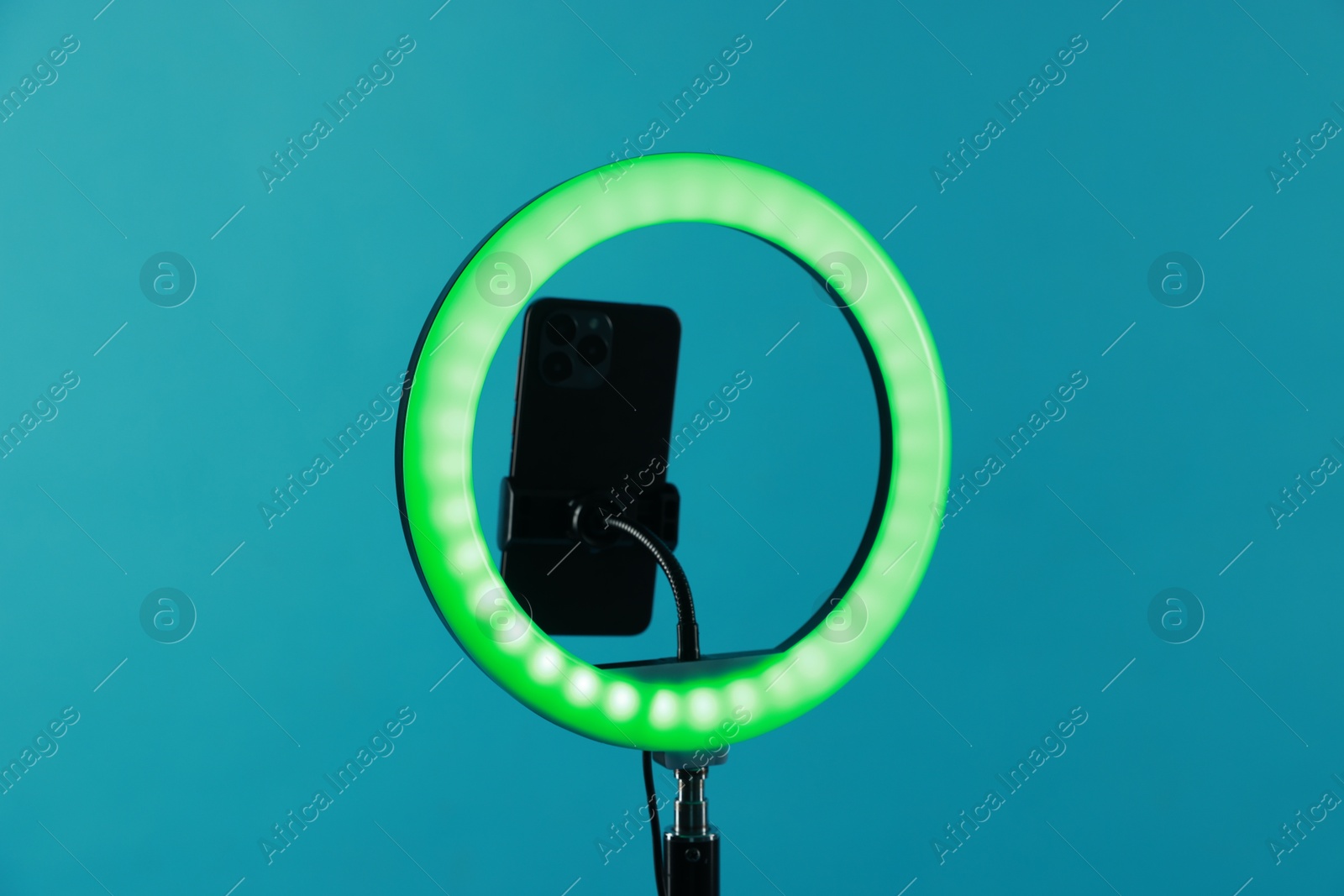 Photo of Ring lamp with smartphone on light blue background