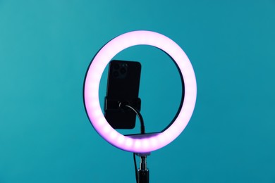 Photo of Ring lamp with smartphone on light blue background