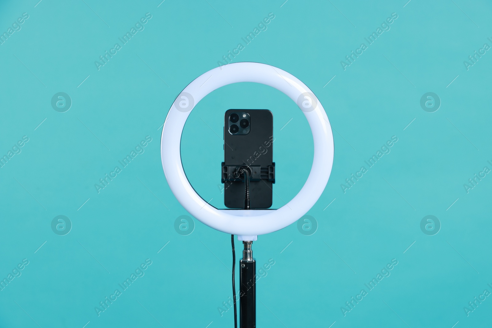 Photo of Ring lamp with smartphone on light blue background