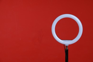 Photo of Ring lamp on stand against red background, space for text