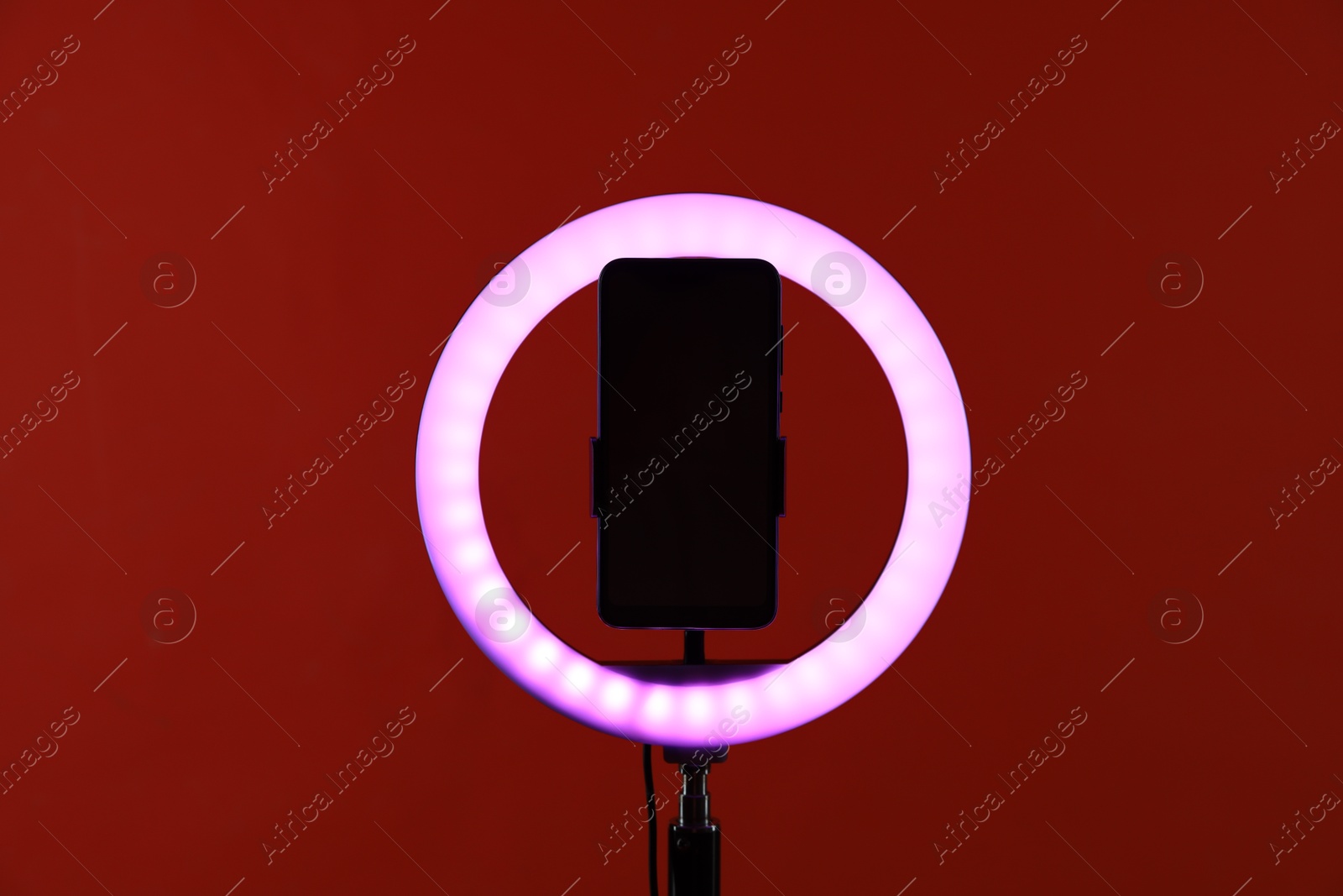 Photo of Ring lamp with smartphone on red background