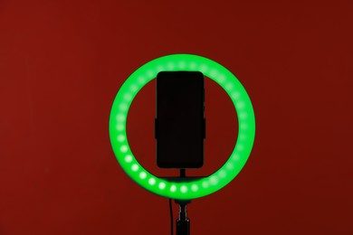 Photo of Ring lamp with smartphone on red background