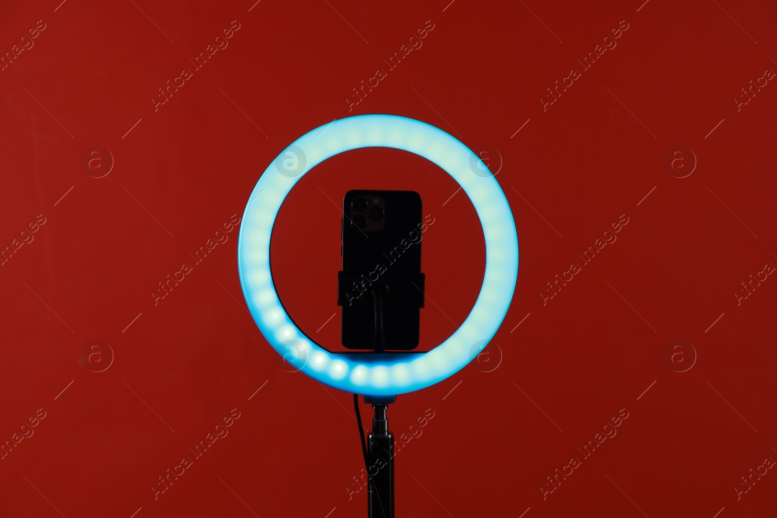 Photo of Ring lamp with smartphone on red background