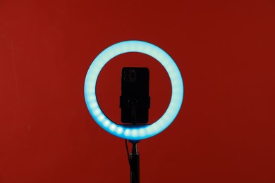 Photo of Ring lamp with smartphone on red background