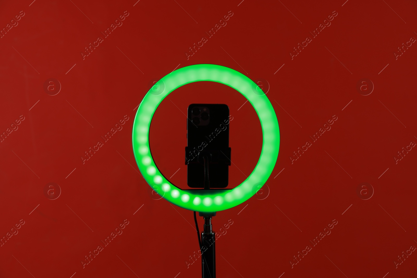 Photo of Ring lamp with smartphone on red background