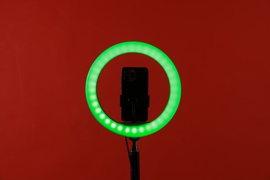 Photo of Ring lamp with smartphone on red background