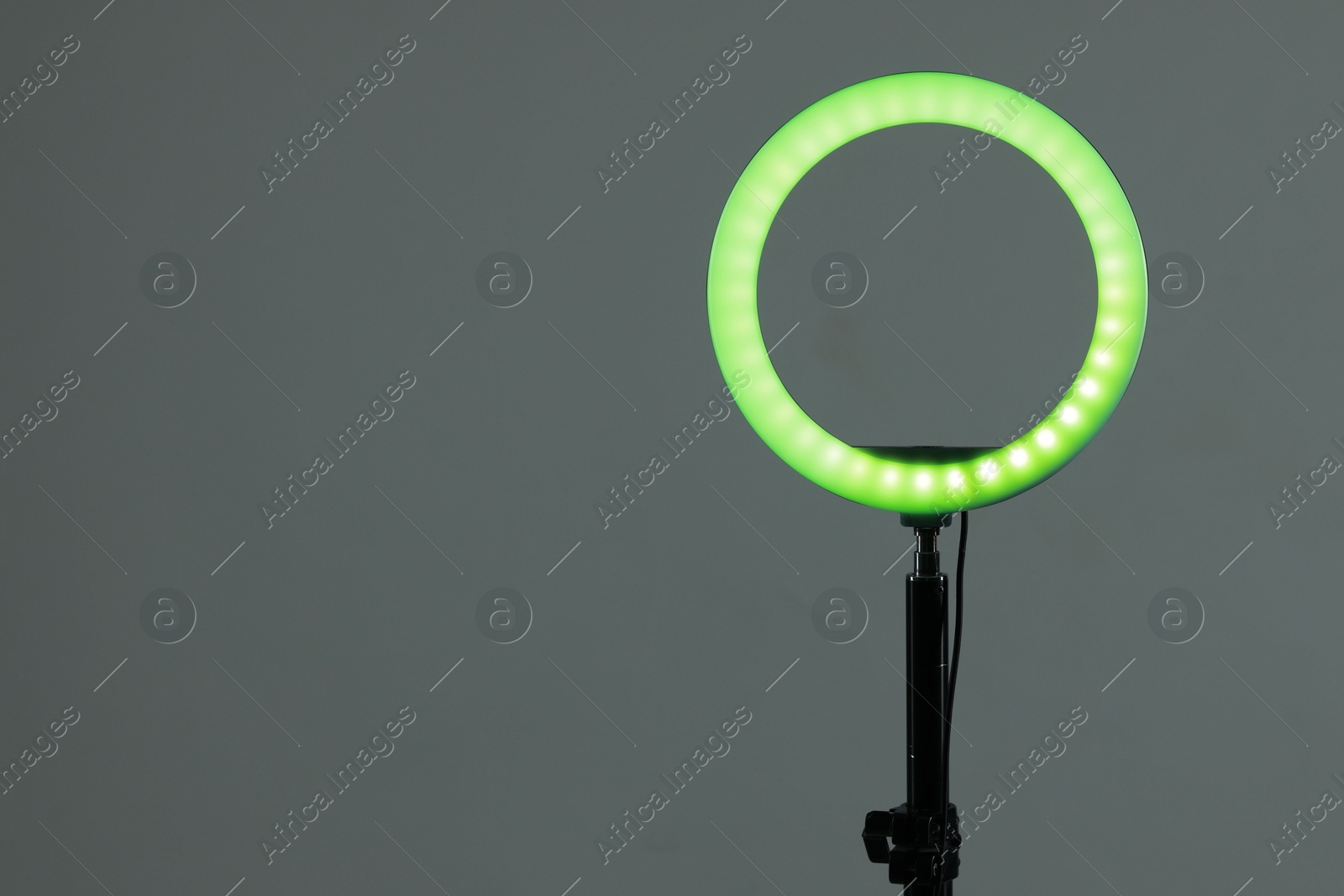 Photo of Ring lamp on stand against grey background, space for text