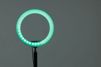 Photo of Ring lamp on stand against grey background, space for text