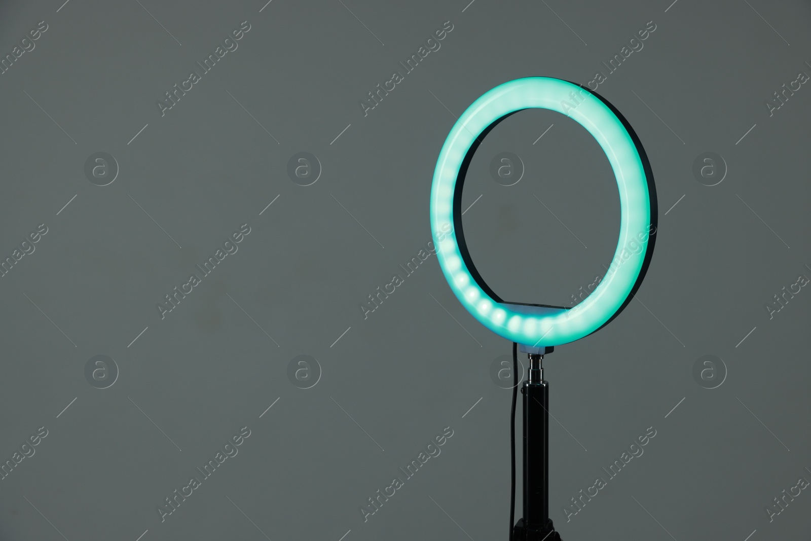 Photo of Ring lamp on stand against grey background, space for text