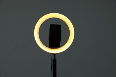 Photo of Ring lamp with smartphone on grey background