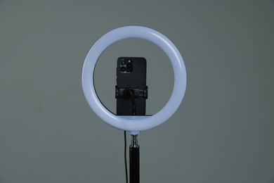 Photo of Ring lamp with smartphone on grey background