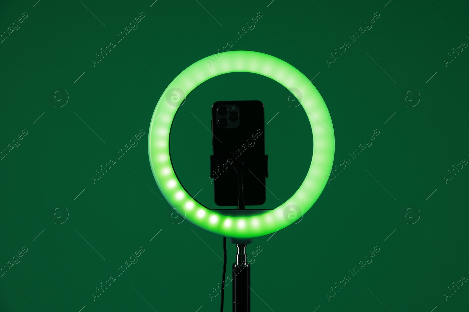 Photo of Ring lamp with smartphone on green background