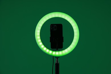 Photo of Ring lamp with smartphone on green background