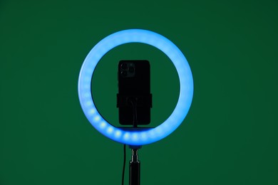 Photo of Ring lamp with smartphone on green background