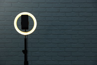 Photo of Ring lamp with smartphone against brick wall, space for text