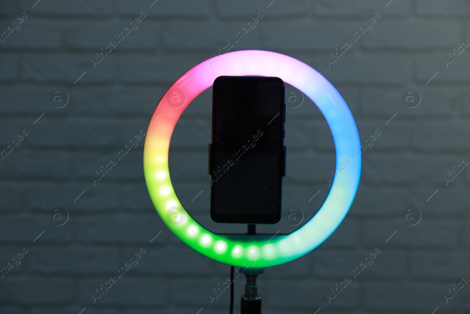 Photo of Ring lamp with smartphone against brick wall