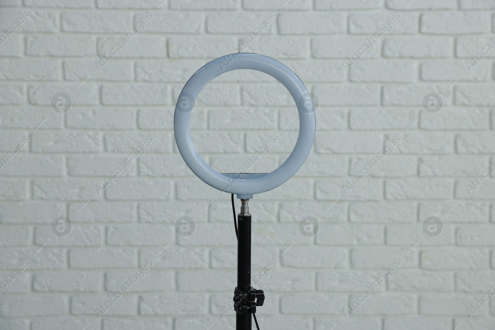 Photo of Ring lamp on stand against white brick wall