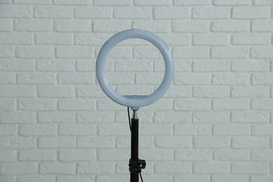 Photo of Ring lamp on stand against white brick wall