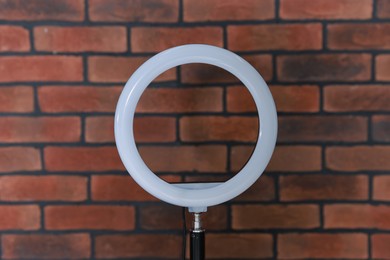 Photo of Ring lamp on stand against brick wall