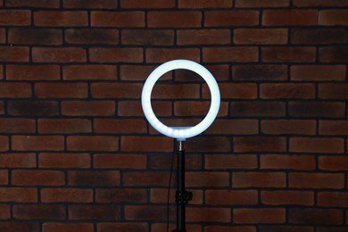 Photo of Ring lamp on stand against brick wall