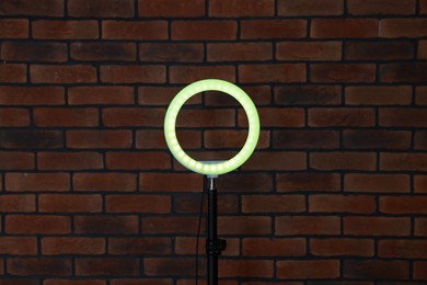 Photo of Ring lamp on stand against brick wall