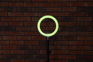 Photo of Ring lamp on stand against brick wall