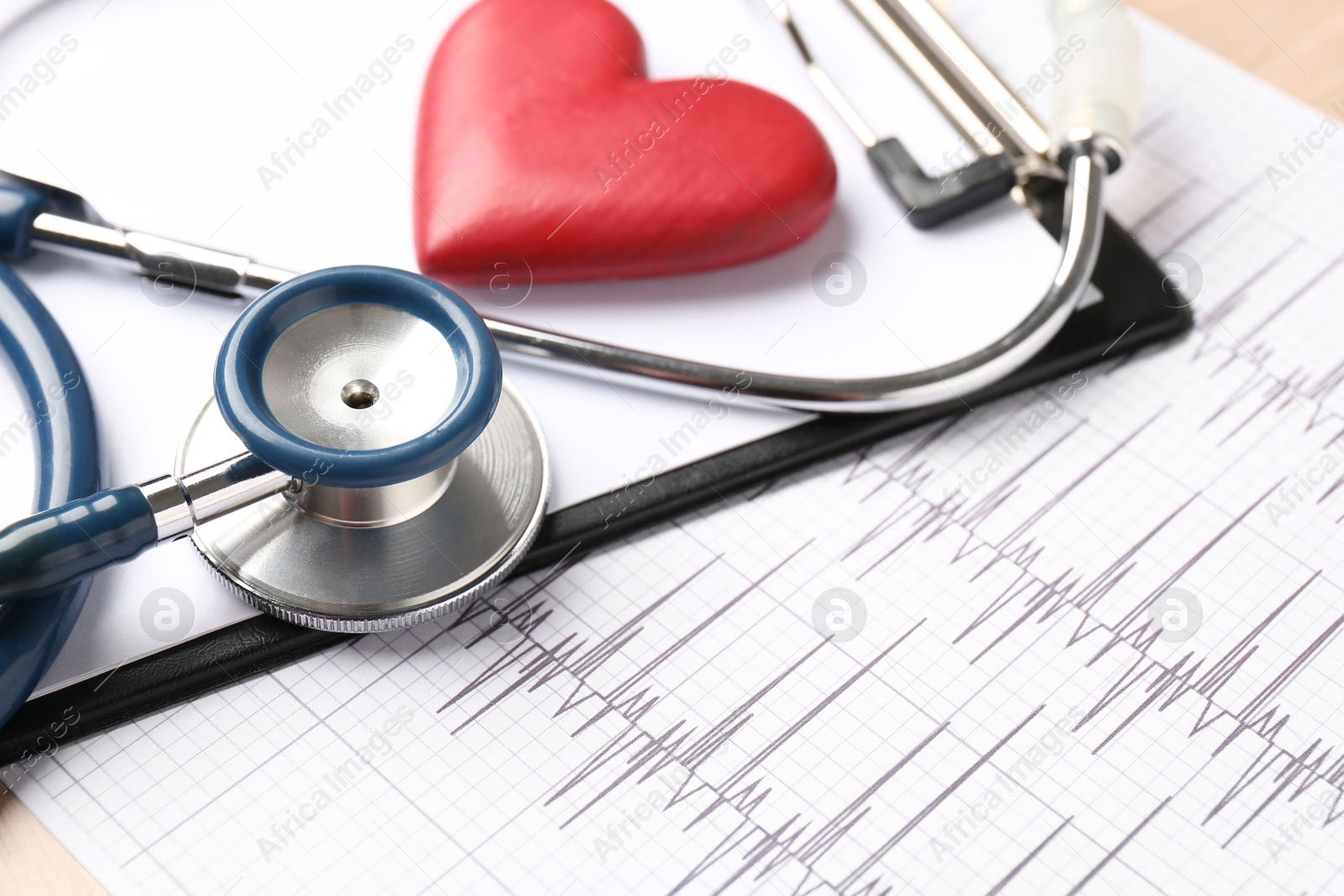 Photo of Cardiology. Cardiogram, clipboard, stethoscope and red decorative heart on table, closeup