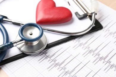 Photo of Cardiology. Cardiogram, clipboard, stethoscope and red decorative heart on table, closeup