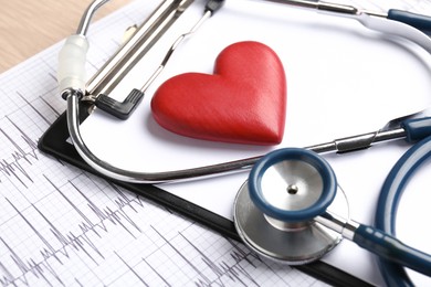 Photo of Cardiology. Cardiogram, clipboard, stethoscope and red decorative heart on table, closeup