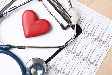 Photo of Cardiology. Cardiogram, clipboard, stethoscope and red decorative heart on wooden table, top view