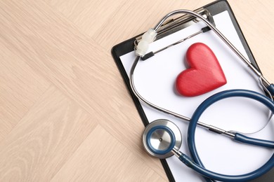 Photo of Cardiology. Clipboard, stethoscope and red decorative heart on wooden table, top view. Space for text