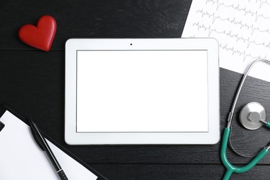 Photo of Cardiology. Flat lay composition with stethoscope and tablet on black wooden table