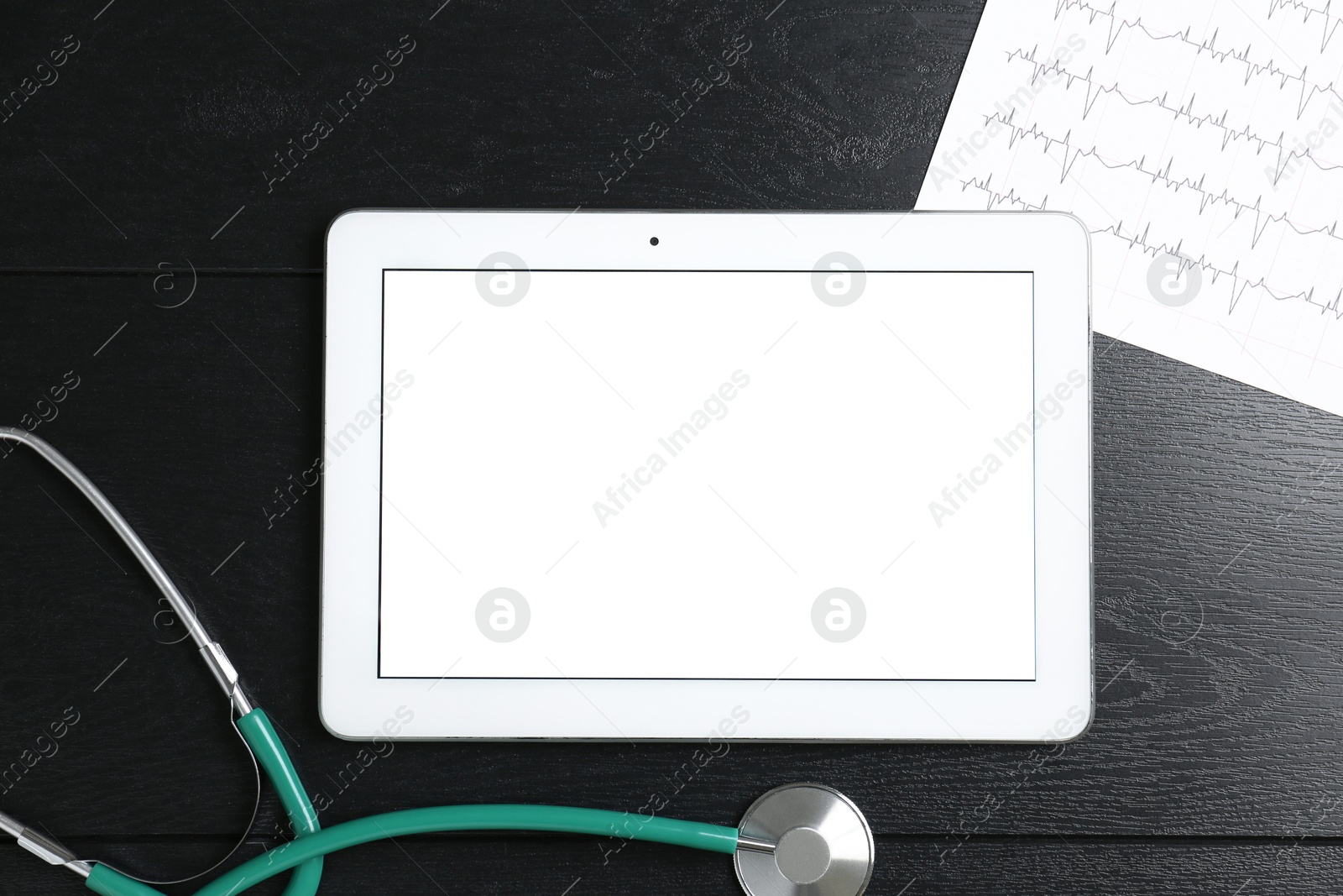 Photo of Cardiology. Tablet, cardiogram and stethoscope on wooden table, flat lay