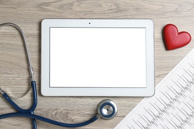 Photo of Cardiology. Tablet, cardiogram, stethoscope, and red decorative heart on wooden table, flat lay