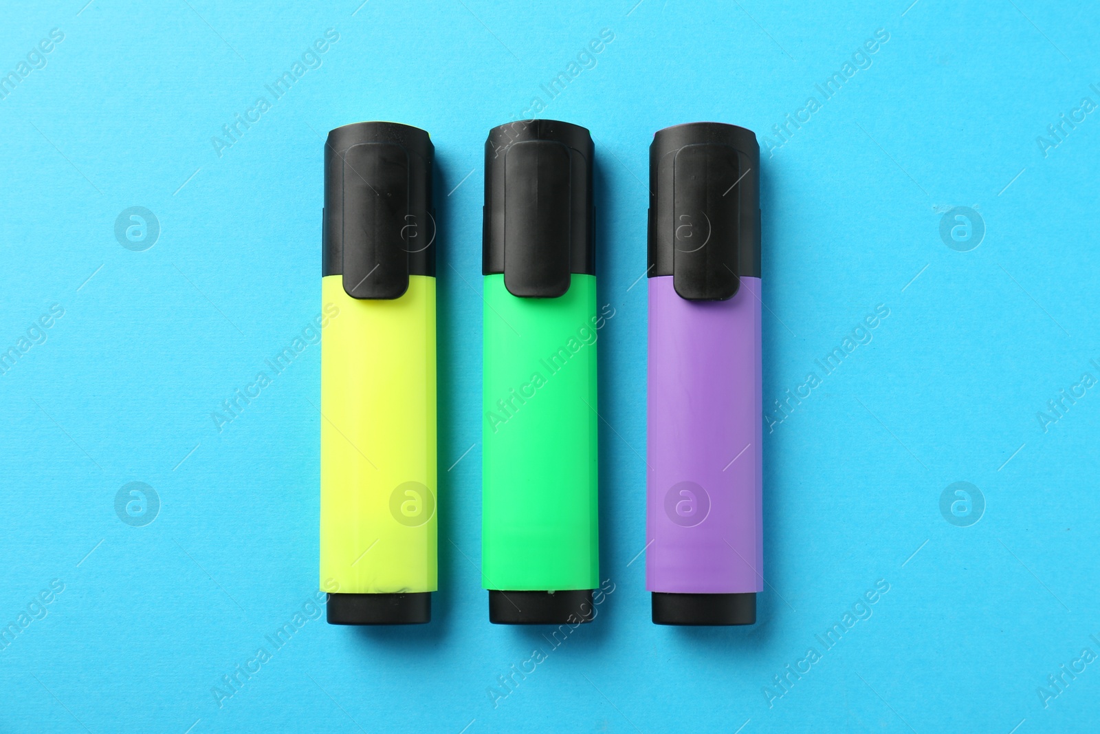 Photo of Bright highlighters on light blue background, flat lay