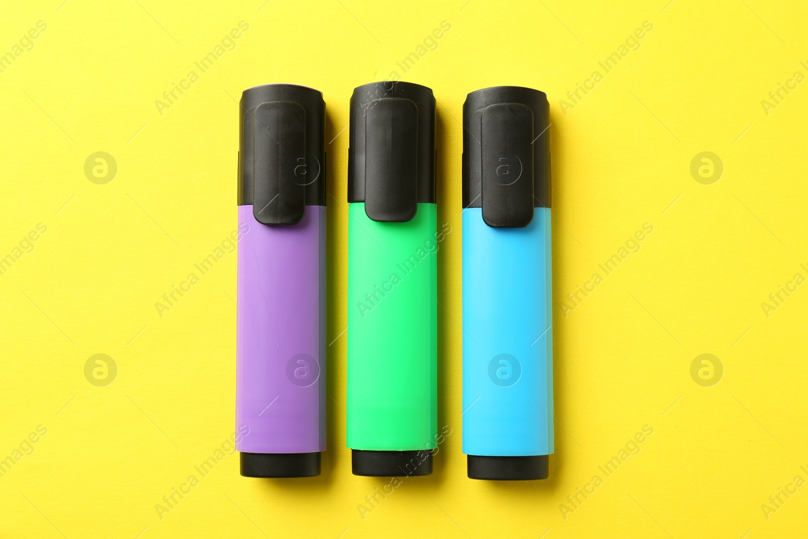 Photo of Bright highlighters on yellow background, flat lay