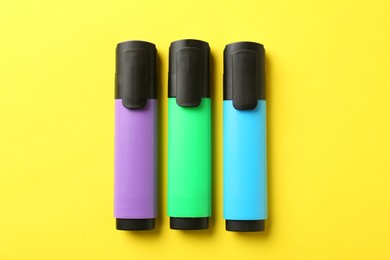 Photo of Bright highlighters on yellow background, flat lay