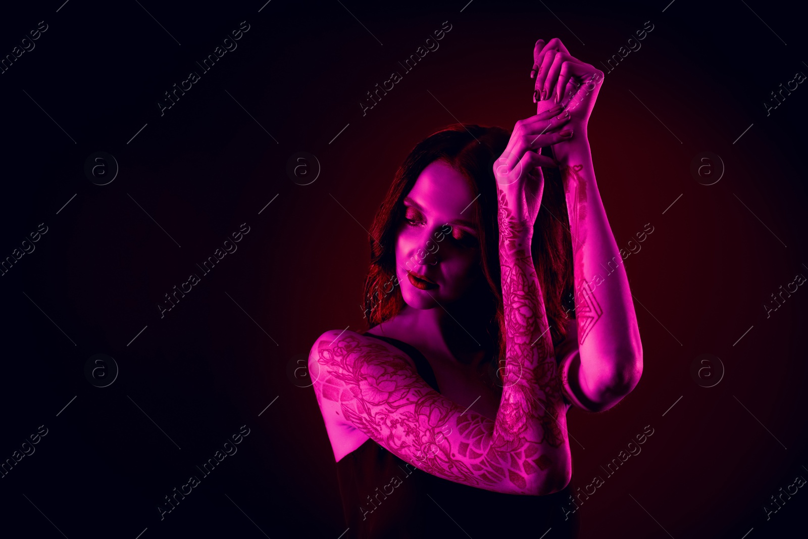 Image of Beautiful woman with tattoos on arms in neon light, space for text