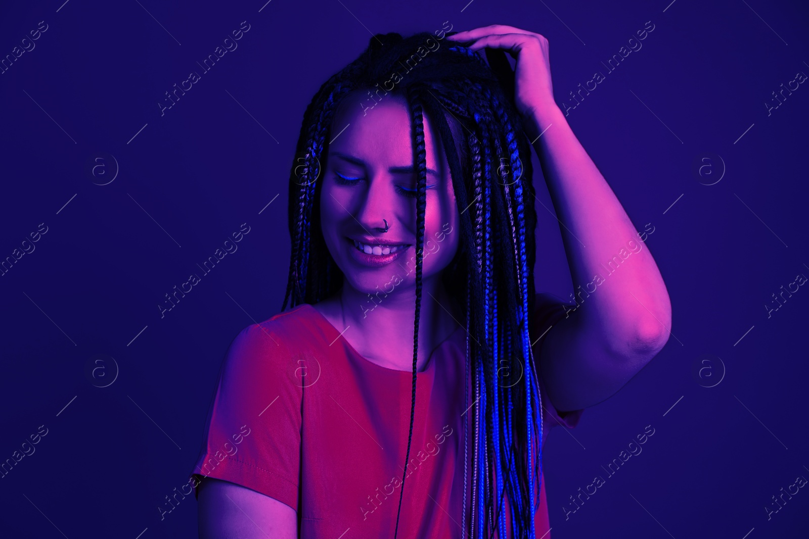 Image of Beautiful young woman with nose piercing and dreadlocks in neon light