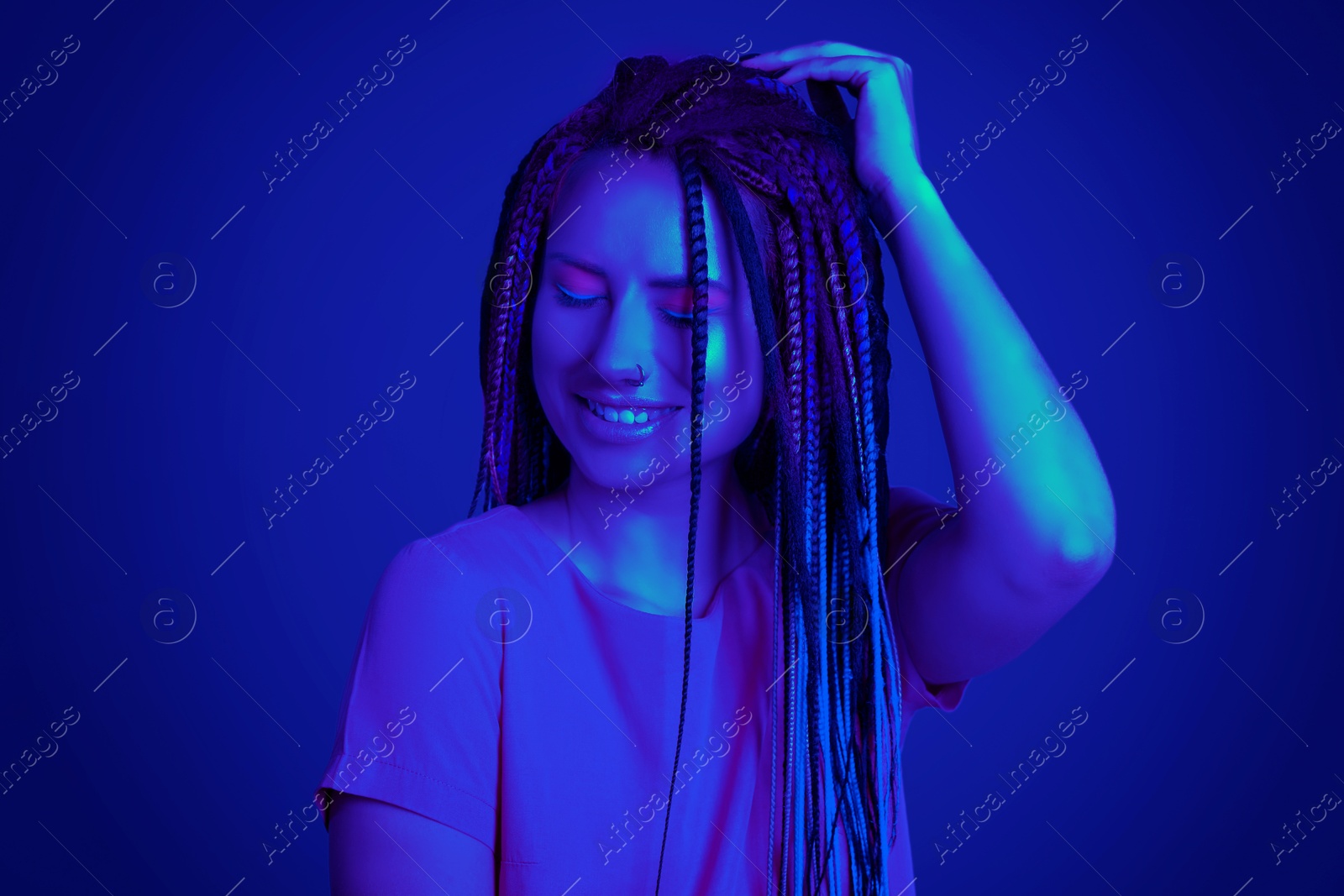 Image of Beautiful young woman with nose piercing and dreadlocks in neon light