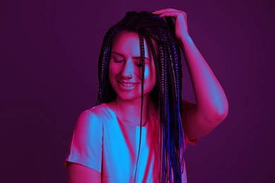 Image of Beautiful young woman with nose piercing and dreadlocks in neon light