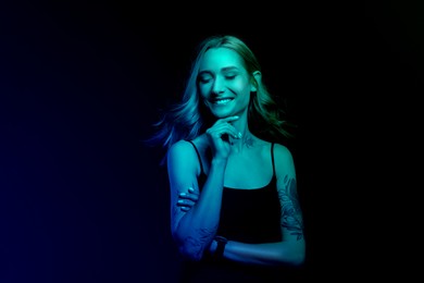 Image of Beautiful woman with tattoos on body in neon light, space for text