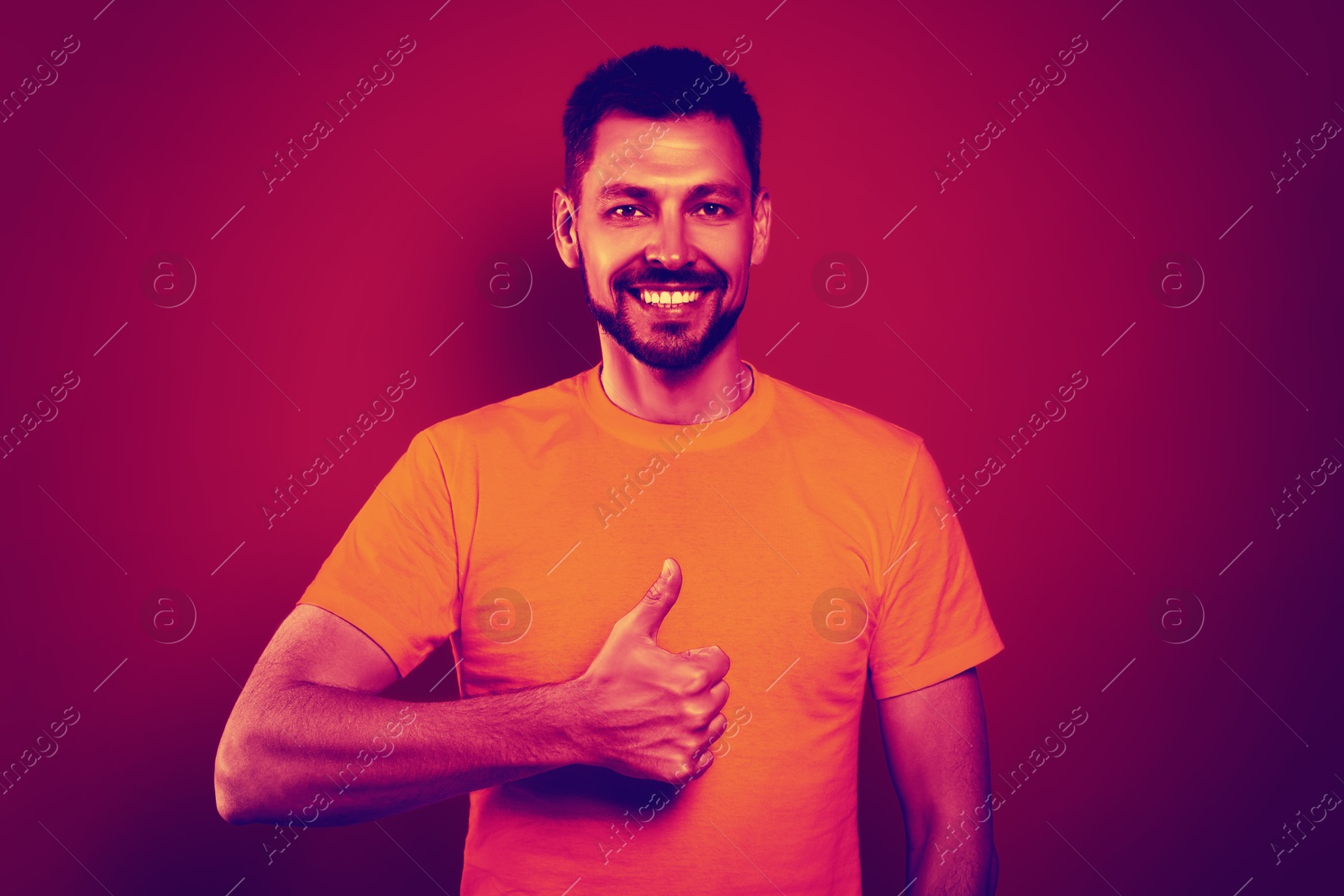 Image of Happy man showing thumbs-up in neon light