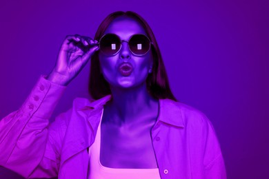 Image of Attractive happy woman with fashionable sunglasses in neon light