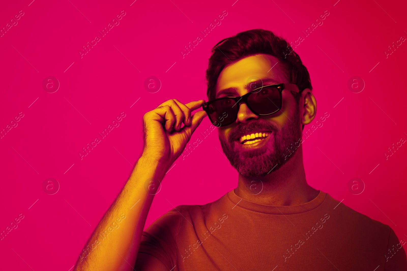 Image of Bearded man with stylish sunglasses smiling in neon light, space for text. Banner design